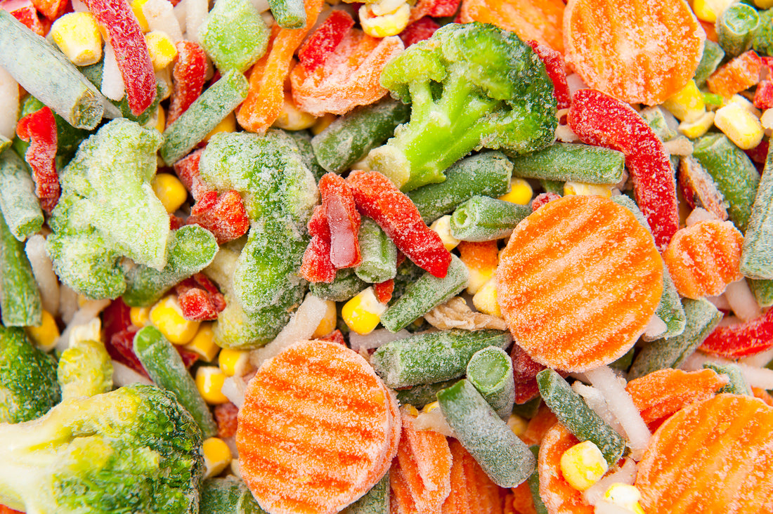 A close-up of frozen vegetables including broccoli, red peppers, corn, green beans and carrot coins