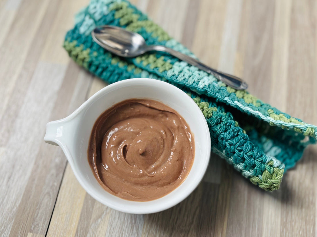 Chocolate whip in a white bowl resting next to a decorative teal napkin and spoon