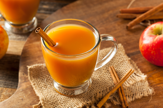 A glass of apple cider with a cinnamon stick 