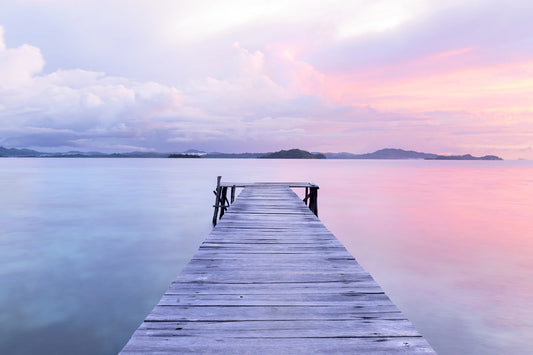 A wooden pier on a calm lake with colors of pink and blue