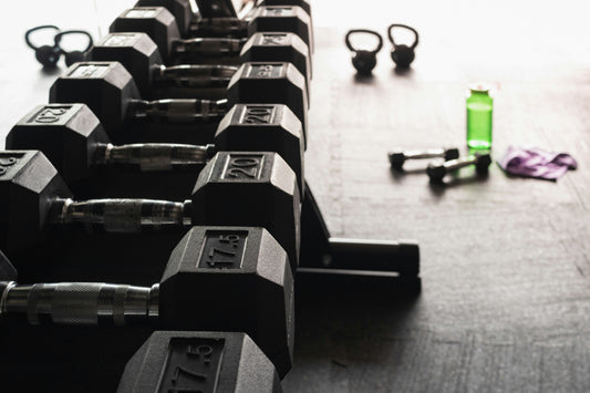 A row of dumbbells with kettlebells and a water bottle