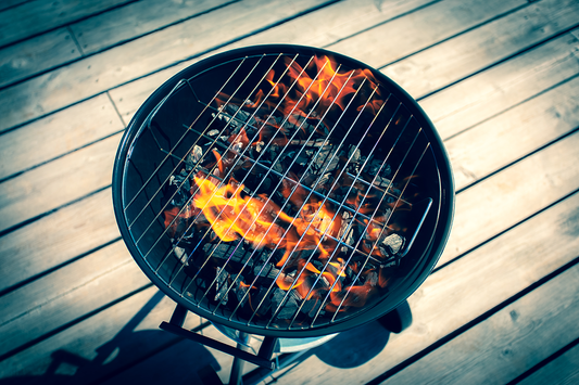 A lit charcoal grill on a wooden deck