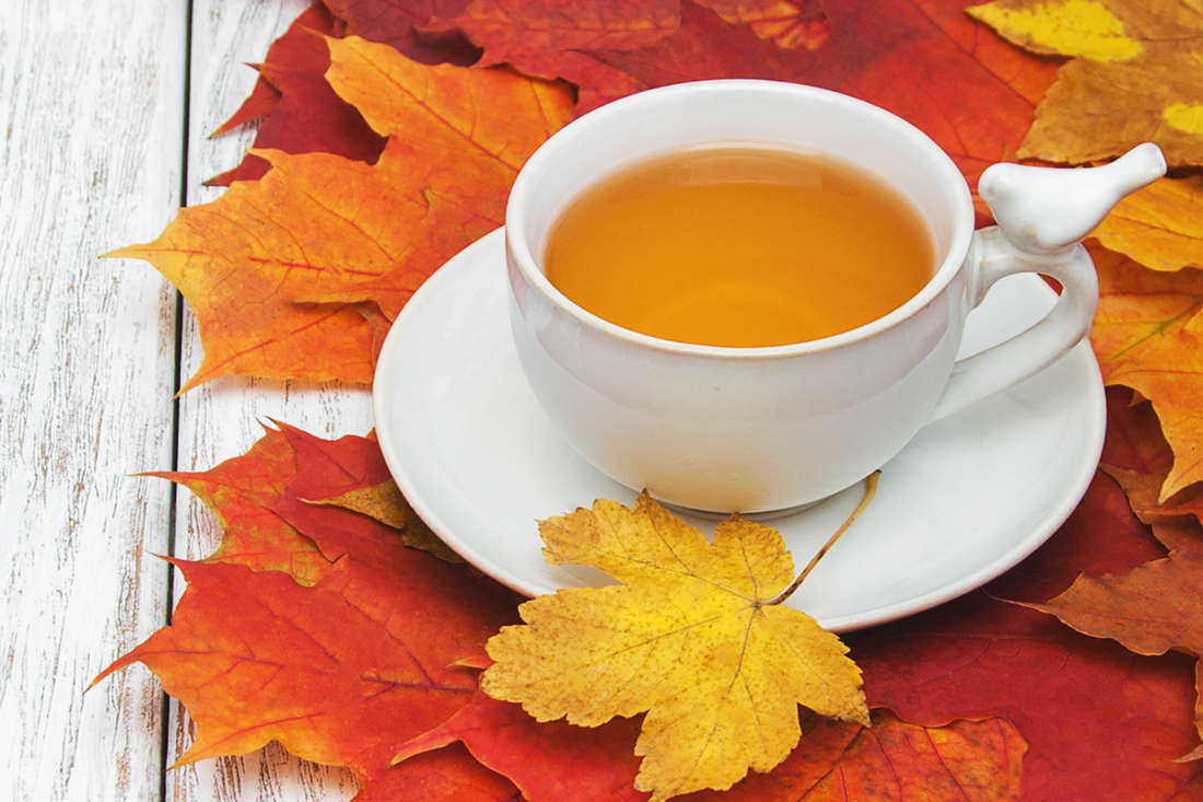 Cup of hot tea on a wooden table with autumn leaves