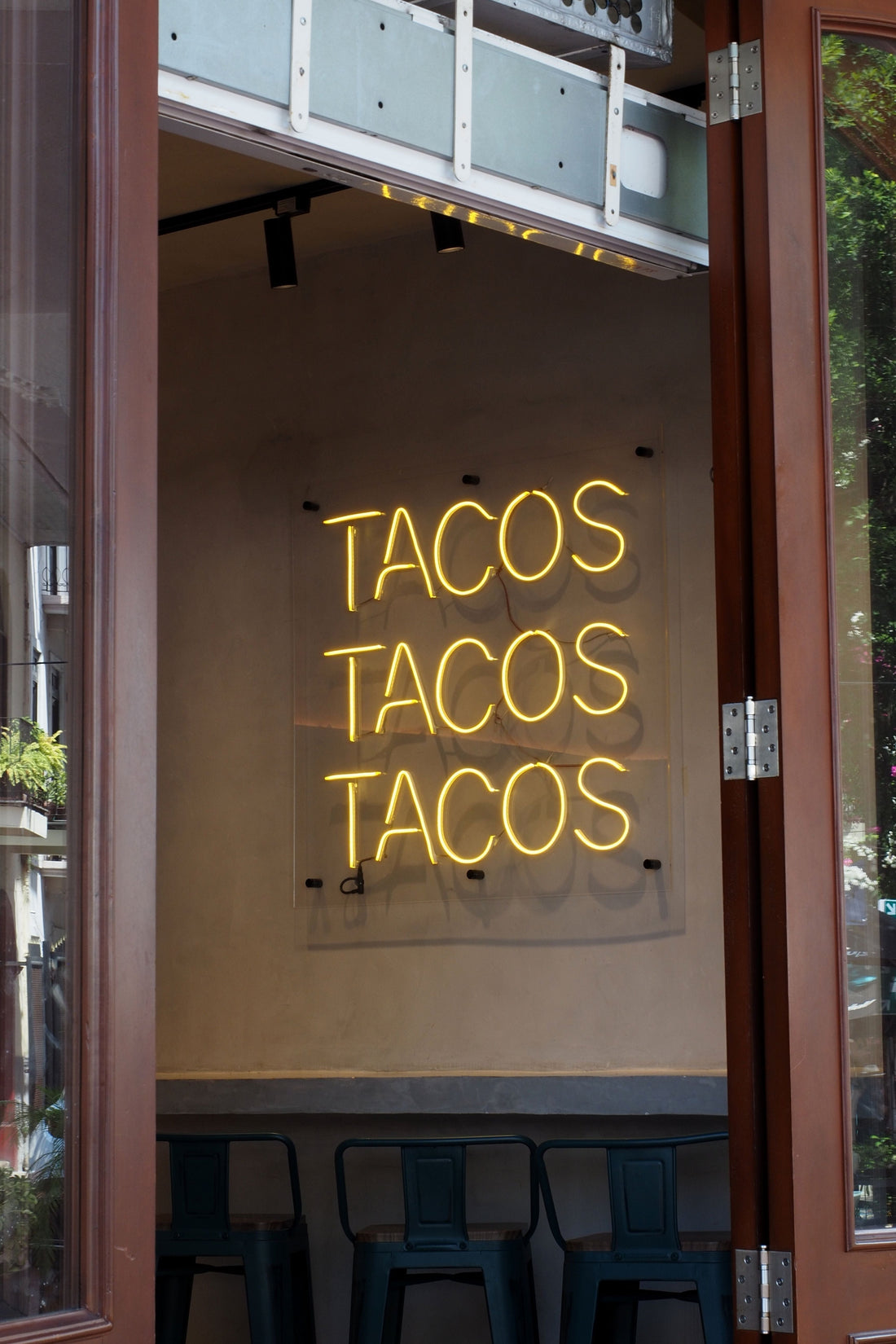 A neon yellow sign with the words "Tacos Tacos Tacos"