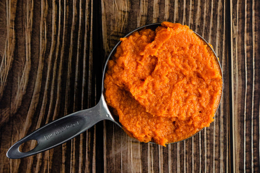 Pumpkin puree in a measuring cup resting on a wooden table